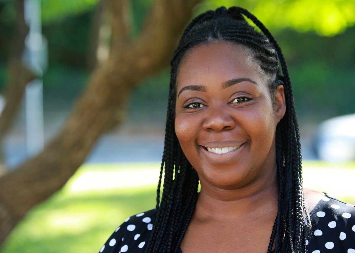 Smiling woman with braids giving a five-star review outdoors