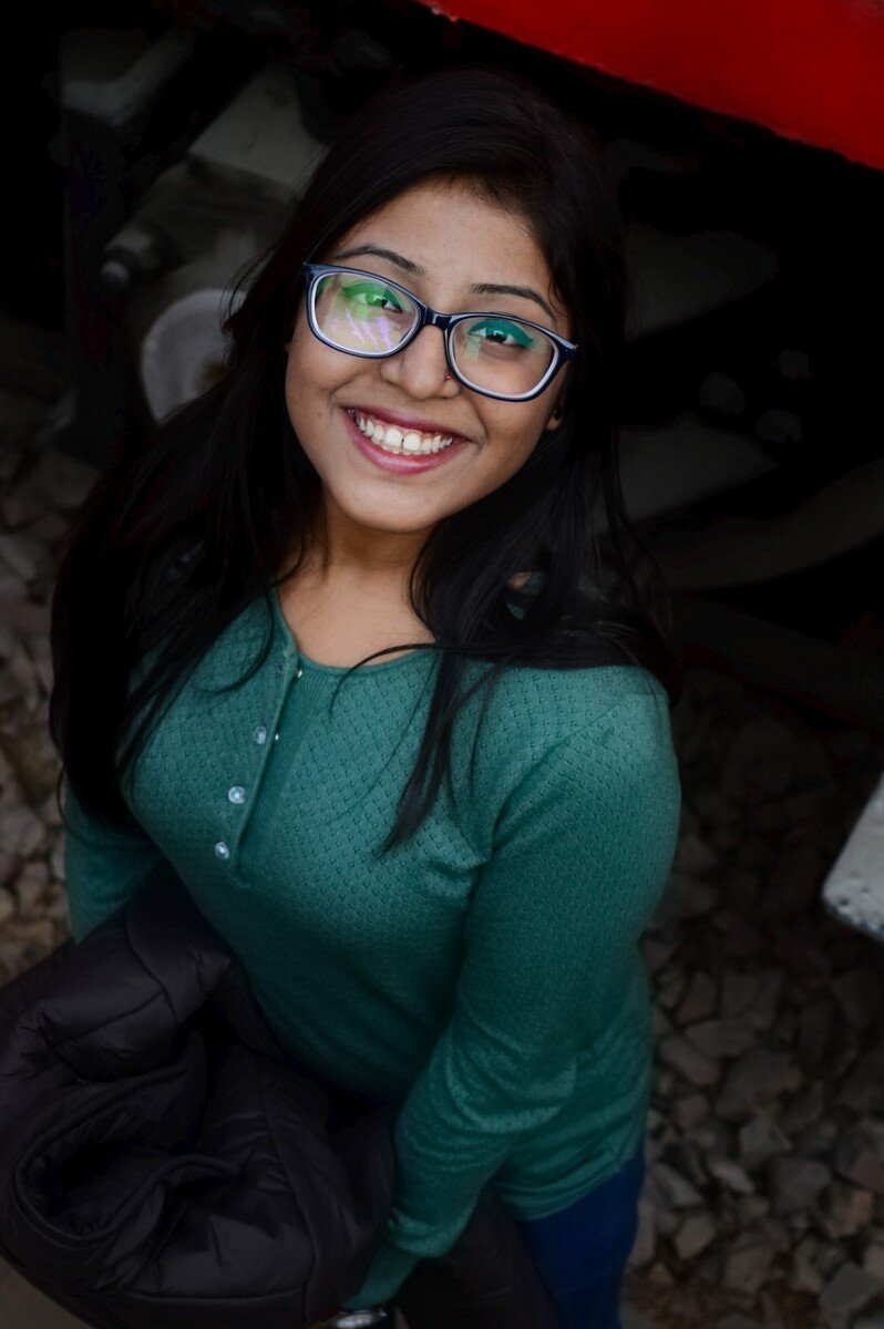 Happy woman in green sweater and glasses sharing a five-star review